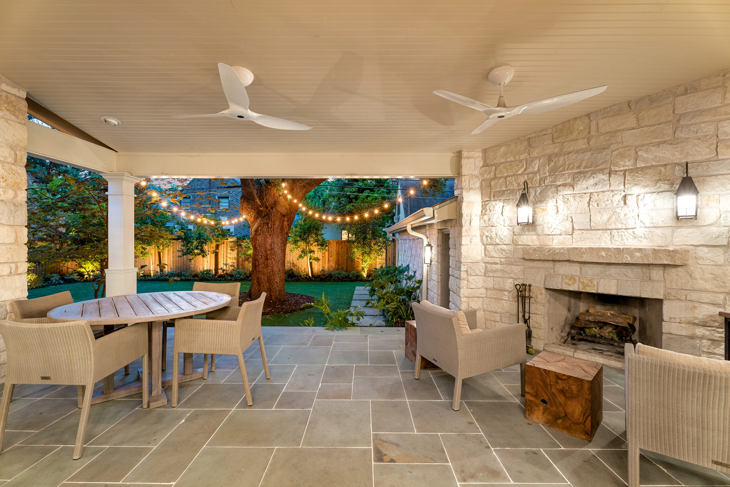 Outdoor terrace with ceiling fans and fireplace. 